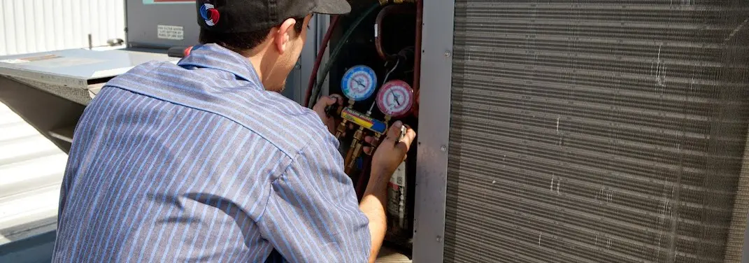 HVAC technician servicing a condenser unit in Providence