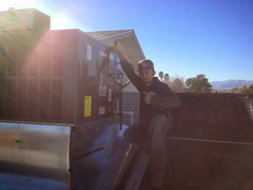 HVAC technician performing Air Duct Cleaning on a rooftop unit in Providence